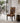 A dining chair with a bold geometric patterned upholstery in orange, brown, black, and cream, styled in a modern minimalist dining room next to a marble-topped side table.