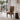A dining chair with a bold geometric patterned upholstery in orange, brown, black, and cream, styled in a modern minimalist dining room next to a marble-topped side table.