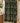 A folded towel or blanket with a bold geometric tribal pattern in black, lime green, and white, hanging on a brass towel bar in a bathroom setting.