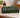 A folded fabric towel or washcloth with a bold African wax print geometric pattern in black, green, and white, resting on a beige marble bathroom counter.