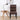 A high-back dining chair with a dark brown and black geometric patterned upholstery, styled in a room next to a wooden side table and a black desk lamp against a white wall.
