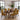 A dining room set featuring a dark wood rectangular table surrounded by six chairs upholstered in a bold yellow, black, and purple geometric patterned fabric, set in a bright modern room with large windows and plants.