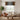 Living room with a beige sofa, round wooden coffee table, and decorative wall hanging.