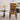 A modern accent chair with a bold black and orange geometric maze pattern on the seat and backrest, styled in a contemporary living room next to a metallic side table with a lamp.