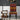 A modern dining chair with a bold geometric and tribal-inspired pattern in terracotta red, orange, black, and cream, styled in a contemporary room next to a wooden side table with a lamp.