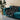 Teal sofa with a black and white patterned throw blanket, potted plant in the background