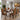 A 7-piece dining set featuring a rectangular wooden table with a silver metal base and six matching upholstered chairs with a vibrant orange, yellow, and black geometric pattern, shown in a modern dining room setting.