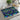 Geometric patterned placemat on a dining table with a cup, teapot, and plant in the background.