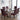 Six dining chairs with navy blue and rust orange geometric patterned upholstery, arranged around a modern glass-top dining table in a bright, contemporary room with large windows.