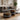 Two round ottomans with a geometric tribal pattern in black, white, and ochre yellow, styled in a modern living room next to a gray sofa.