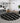 Round black and white patterned rug in a living room with a gray sofa and decorative wall art.