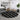 Round black and white patterned rug in a living room with a gray sofa and decorative wall art.