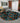 Geometric patterned rug in a living room setting with a gray sofa and decorative elements.