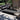 Outdoor patio with a black and white patterned rug, gray sectional sofa, and potted plants.