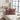 Decorative pillow with red and yellow pattern on a beige sofa in a bright room.