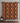Decorative towel with geometric pattern on a tiled wall, next to a bottle and stone on a shelf.
