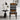 A modern accent chair with a bold geometric and tribal-inspired pattern in black, brown, and white, styled in a minimalist room next to a black side table and lamp.