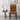 A modern dining chair with a mustard yellow and black geometric tribal patterned fabric, styled in a minimalist room next to a side table with a lamp and vase.