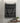Black and white patterned towel hanging on a tiled wall with a small plant and soap dish below.