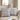 Black and white patterned pillows on a beige sofa with a mirror and decorative items in the background.