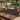 Decorative outdoor rug with geometric pattern on a wooden deck surrounded by plants.